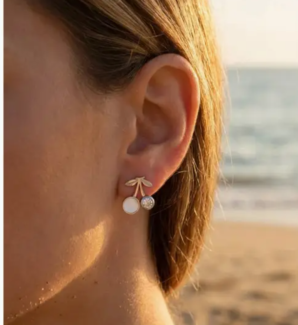Boucles d'oreilles cerises avec perle nacrée et strass portées sur plage