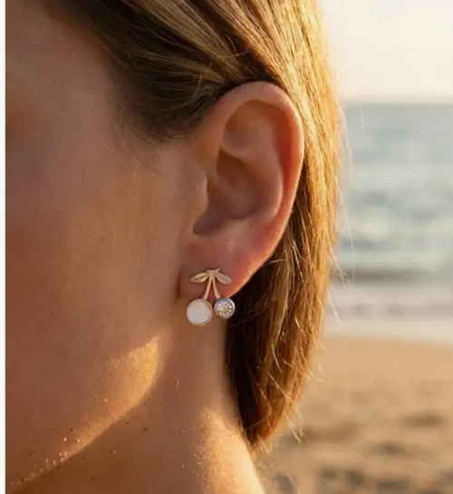 Boucles d'oreilles cerises avec perle nacrée et strass portées sur plage