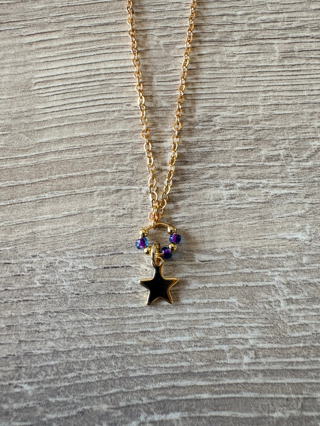 Collier chaîne dorée avec pendentif étoile noire et perles violettes irisées